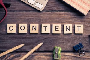  A top-down view of wooden scrabble-style tiles spelling out the word "CONTENT" laid across a dark, rustic wooden desk surface.